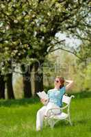 Young woman relaxing under blossom tree in spring