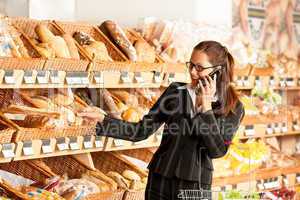 Grocery store: Young business woman holding mobile phone