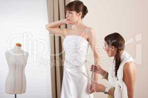 Fashion model fitting white wedding dress by designer