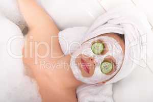 Body care series - Young lady with facial mask and cucumber