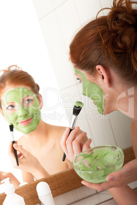 Body care series - Young woman applying green facial mask