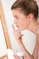 Body care series - blond woman applying cream on face