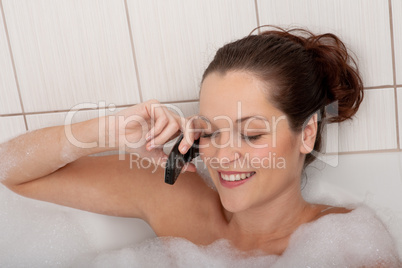 Body care series - Young woman in the bathtub with mobile phone