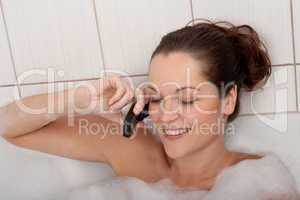 Body care series - Young woman in the bathtub with mobile phone