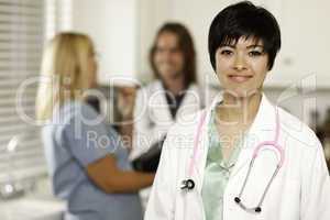 Pretty Doctor Smiles at Camera as Collegues Talk