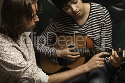 Young Musician Teaches Female Student To Play the Guitar