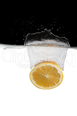 Eine Orangenscheibe fällt ins Wasser