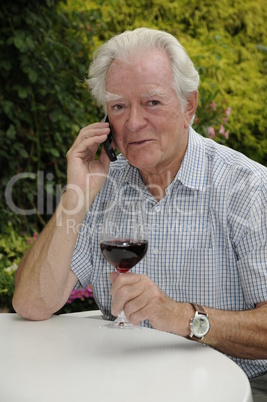 Rentner mit Handy und Rotwein