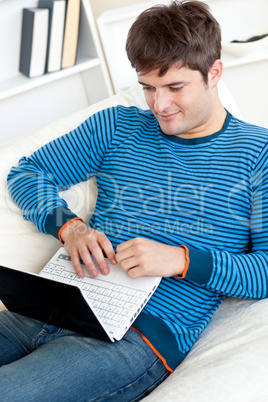 man using his laptop lying on the sofa