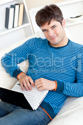 man working on his laptop lying on the couch