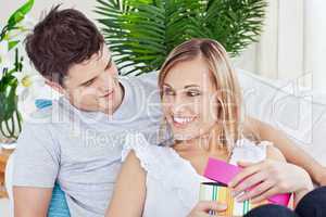 couple lying on the sofa with a present