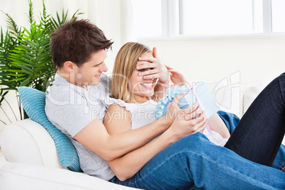 couple lying on the sofa with a present