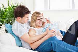 couple lying on the sofa with a present