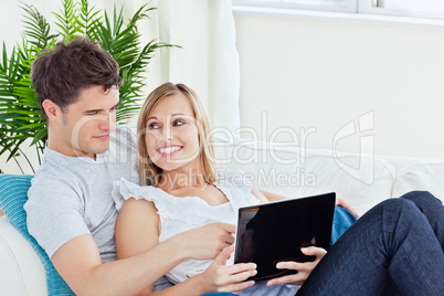 young couple sitting on a sofa using laptop