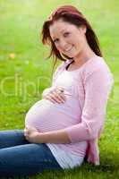 pregnant woman sitting on the short grass