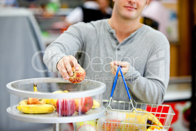 man putting apples in his shopping basket