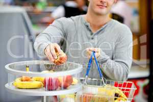 man putting apples in his shopping basket