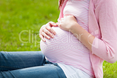 Pregnant young woman sitting on the grass