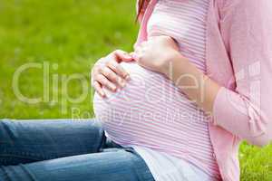 Pregnant young woman sitting on the grass