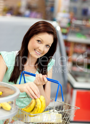 woman putting bananas in her shopping-basket