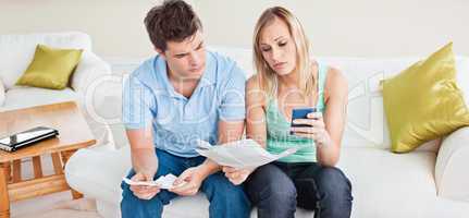 couple calculating bills sitting on the sofa