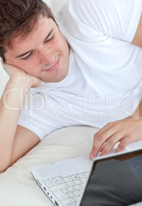 man using his laptop lying on his bed man using his laptop lying on his bed