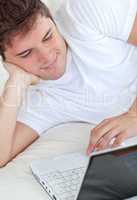 man using his laptop lying on his bed