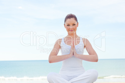 woman practicing yoga on the beach