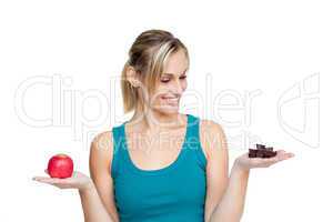 Young woman comparing apple with chocolate