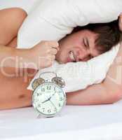 angry man stressed by his alarm clock
