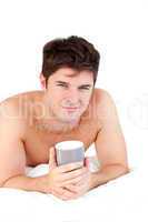 male adult holding a cup on his bed