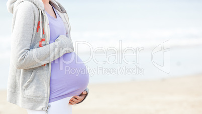 Pregnant young woman walking on the beach