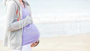 Pregnant young woman walking on the beach
