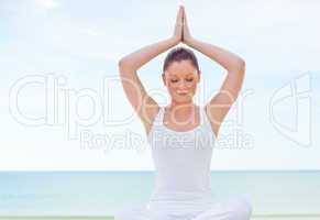 woman practicing yoga by the beach