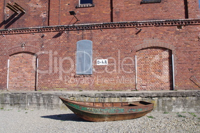 Rostiges grünes Boot vor Ziegelsteinfassade