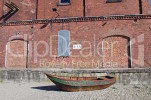 Rostiges grünes Boot vor Ziegelsteinfassade