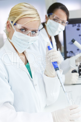 Female Research Scientist With Pipette & Flask In Laboratory