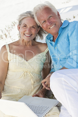 Happy Senior Couple using Laptop Computer on a Beach