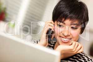 Pretty Smiling Multiethnic Woman with Cell Phone Using Laptop