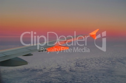 Flugzeugflügel mit Sonnenuntergang über den Wolken
