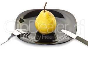 Yellow pear on a black plate with fork and knife
