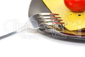 Red tomato and cheese on a black plate with fork