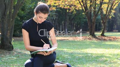 Girl on meadow writes to notebook