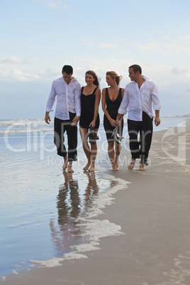 Four Young People, Two Couples, Holding Hands On A Beach