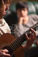 Young Musician Plays His Acoustic Guitar as Friend Listens