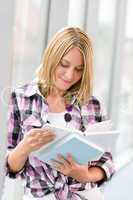 Happy young blond woman holding books