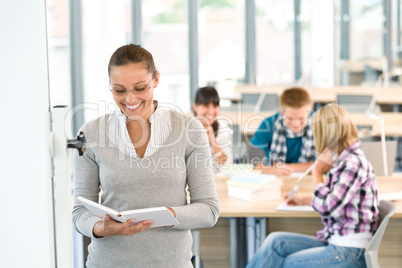 Female teacher with book and students in classroom