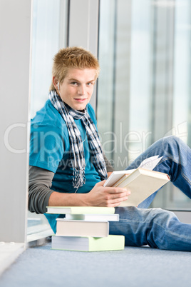 Young man with earbuds and books