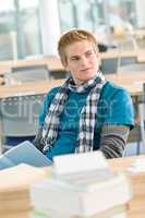 Male student with book sitting in classroom