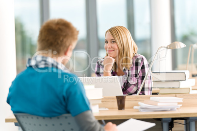 Two students with books and laptop in classroom